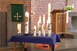 Viele Taufkerzen unterschiedlicher Gre stehen auf einem Tisch im Altarraum der Trinitatiskirche.