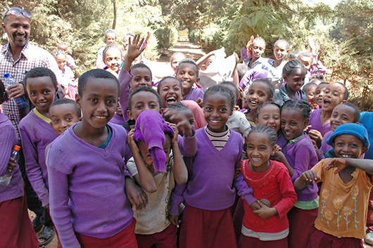 Eine Gruppe von thiopischen Kindern winkt freudig und lachend in die Kamera.