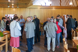 Blick in den groen Gemeinderaum, wo zahlreiche Besucherinnen und Besucher des Gottesdienstes in Gesprche vertieft sind.